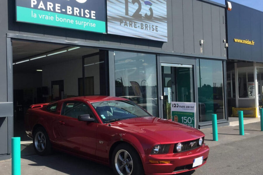 Photo d'une Ford Mustang rouge devant l'enseigne 123 Pare-Brise.